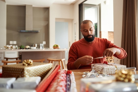 man wrapping holiday gifts