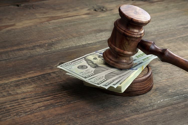 Money being crushed by a Gavel on a wooden table